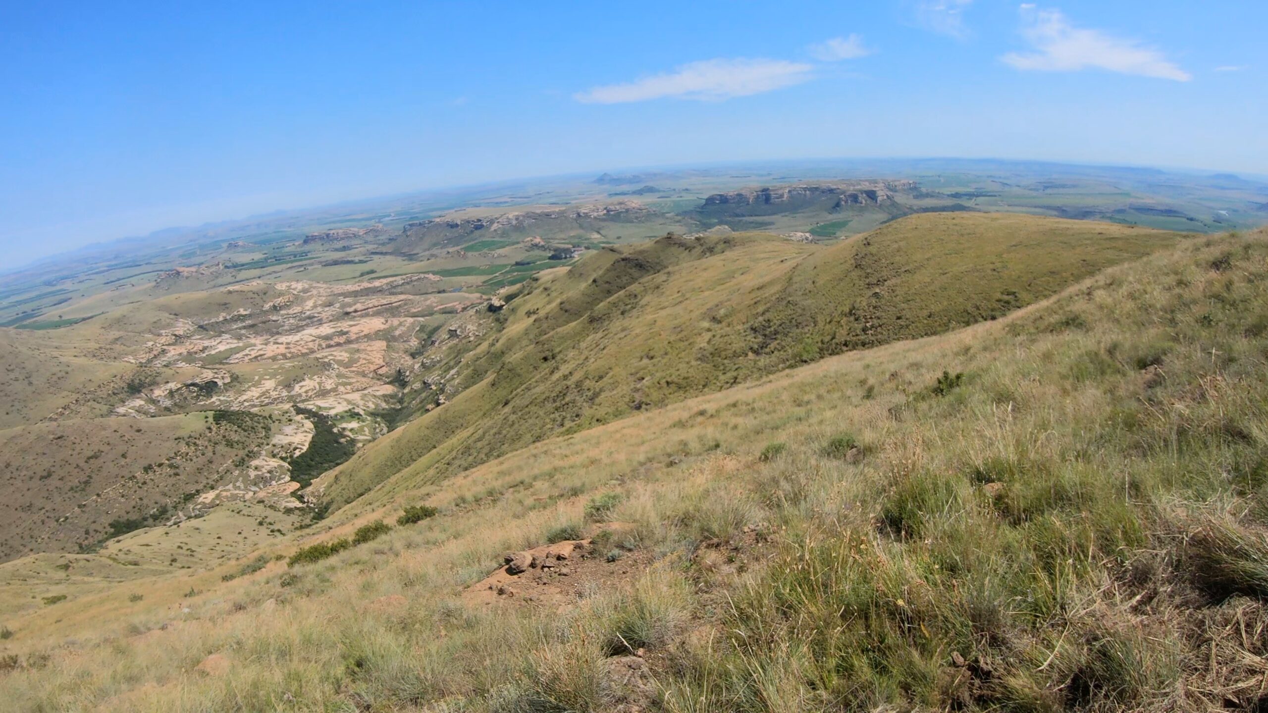 Ridge-line view over sandstone koppies and farmland toward Lesotho from the Maluti Mountains.